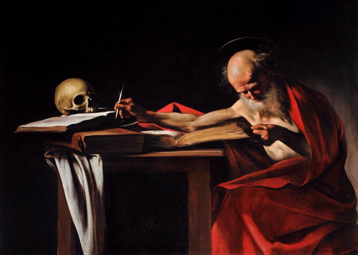 A bald white man with a white beard in a red robe writing in his study with a skull perched on an open book.
